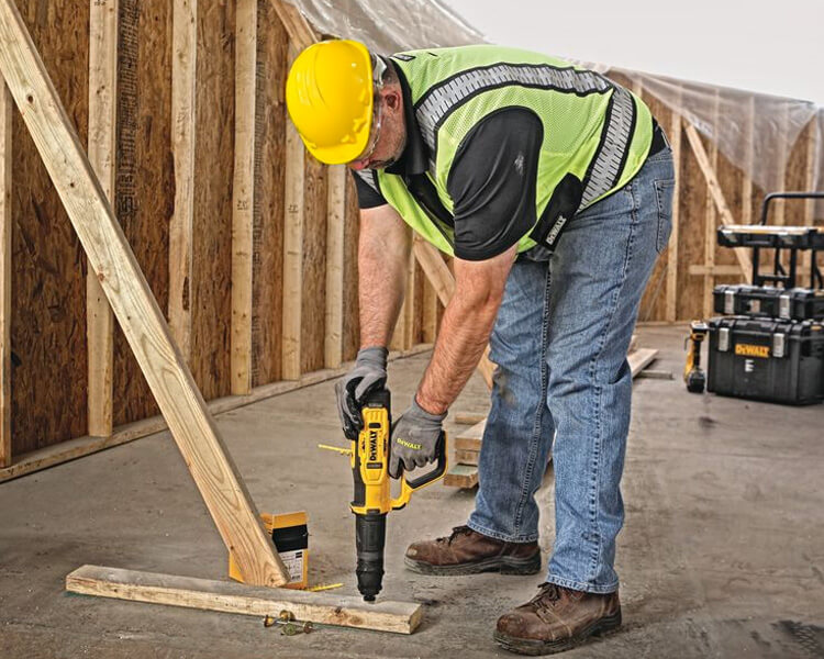 Construction worker using a Dewalt Screw Gun to secure wood beams into concrete, demonstrating precision and ease