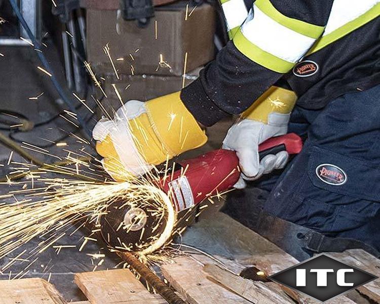 Worker using protective gear and angle grinder on metal bar, sparks flying in workshop - ITC industrial tools in action